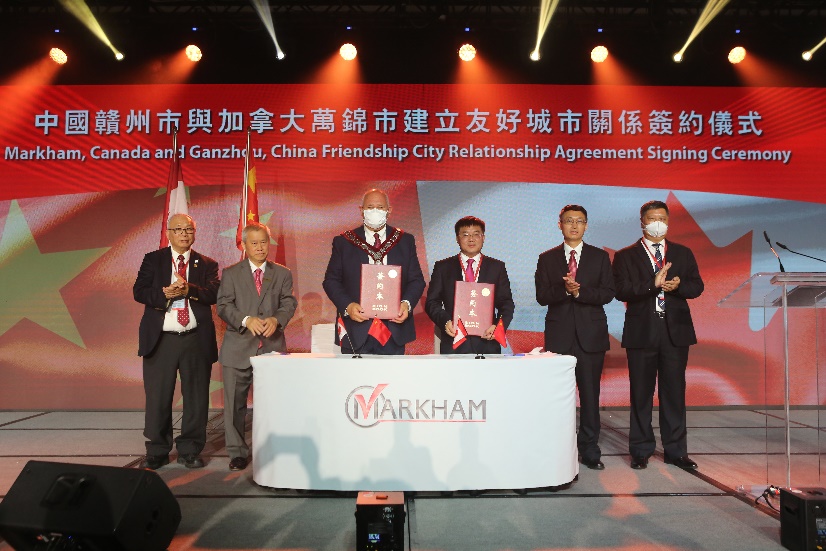 A group of men standing on a stage with a sign Description automatically generated with low confidence