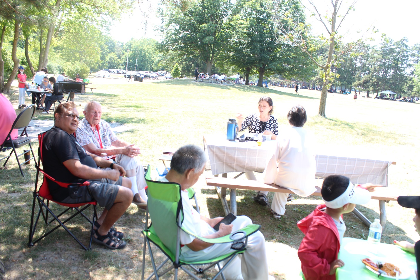 A group of people sitting around a table outside Description automatically generated with medium confidence