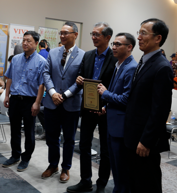 A group of men standing together holding a plaque Description automatically generated