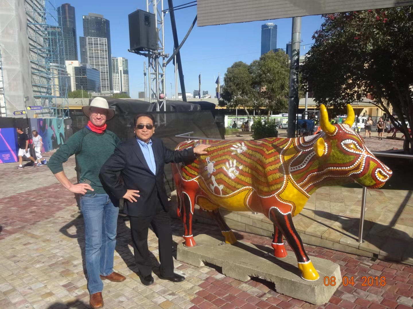 A couple of people posing with a statue of a cow

Description automatically generated