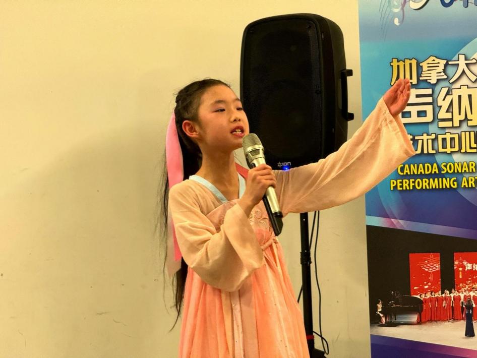 A child in a pink dress holding a microphone

Description automatically generated