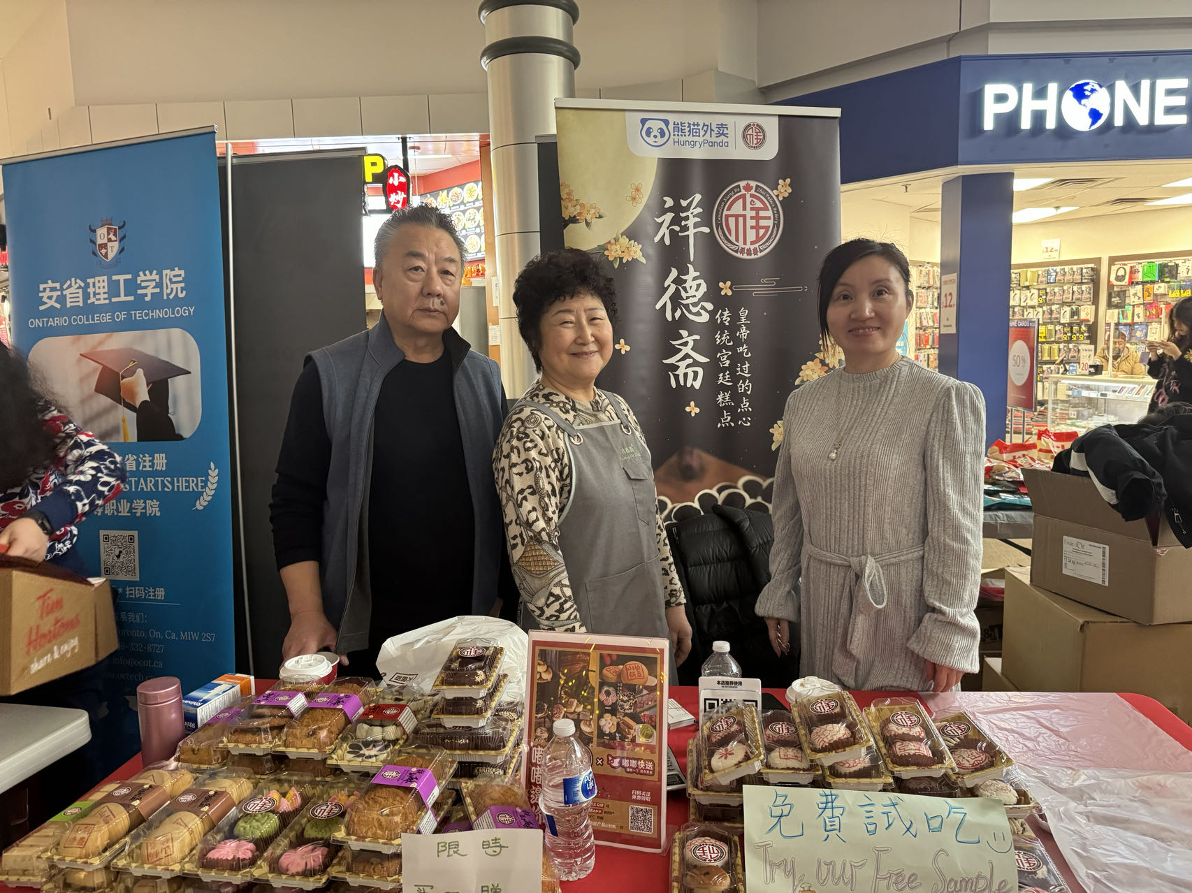 A group of people standing in front of a table of food

Description automatically generated