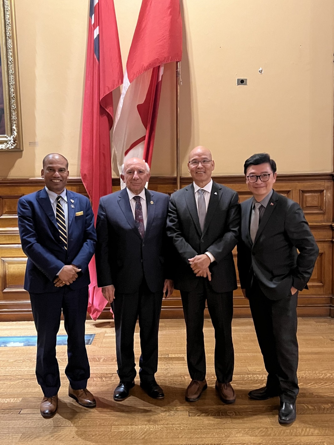 A group of men in suits standing in front of a flag

Description automatically generated