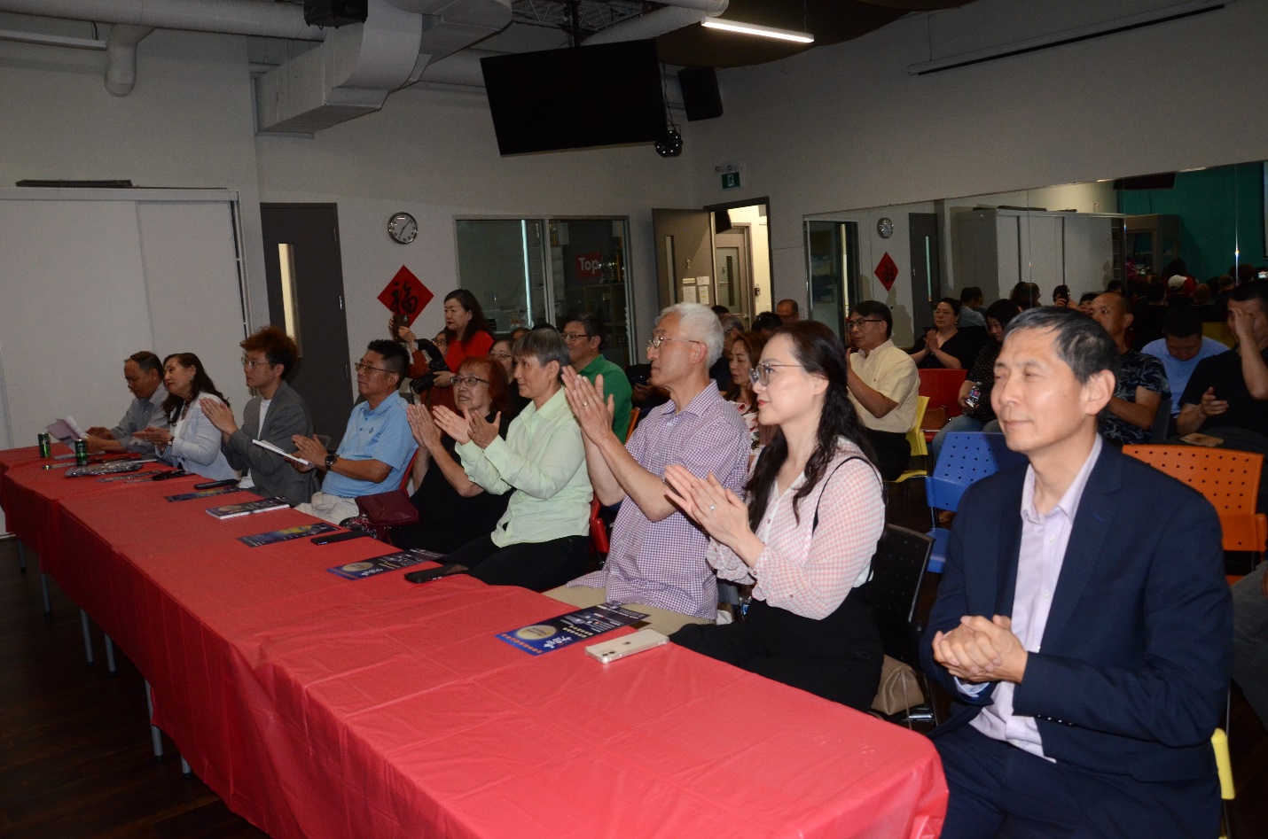 A group of people clapping at a meeting Description automatically generated