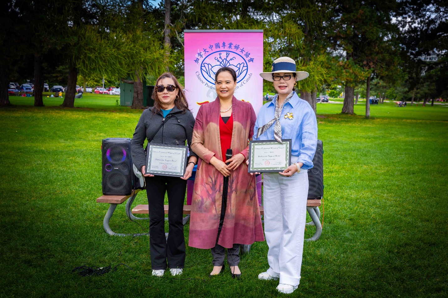 A group of people standing in a park holding certificates Description automatically generated