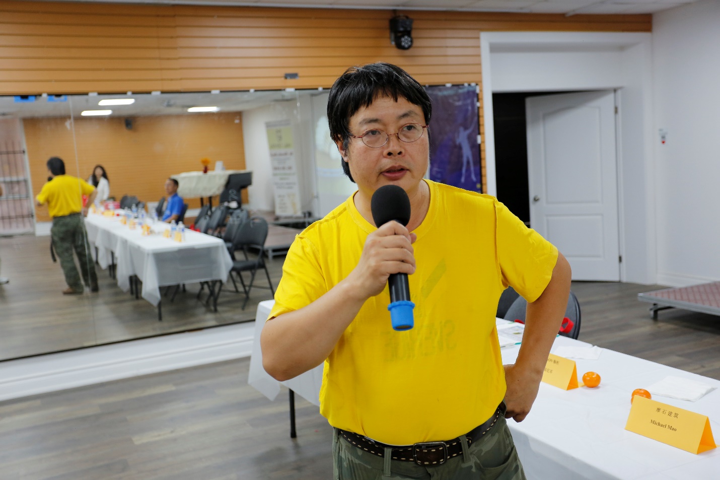 A person in a yellow shirt holding a microphone

Description automatically generated