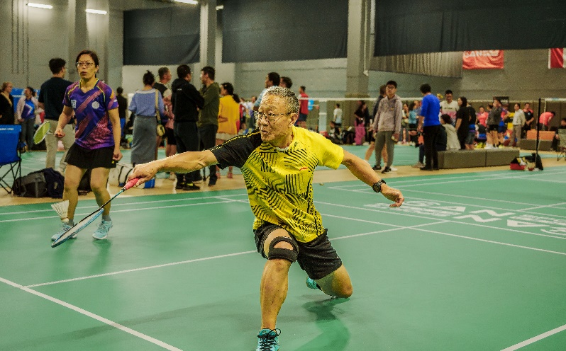 A person in a yellow shirt with a racket in his hand

Description automatically generated