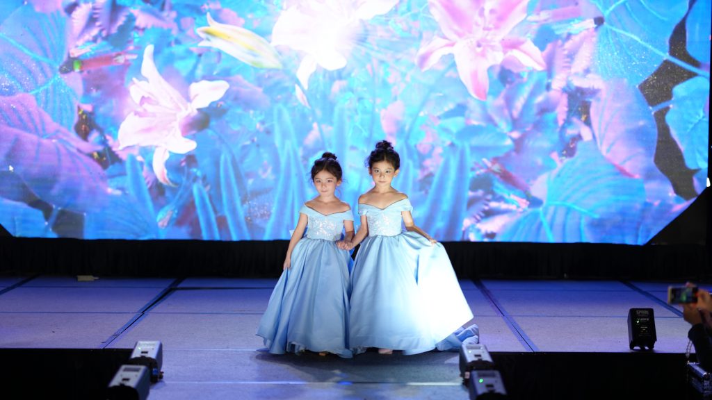 Two girls in dresses on a stage Description automatically generated