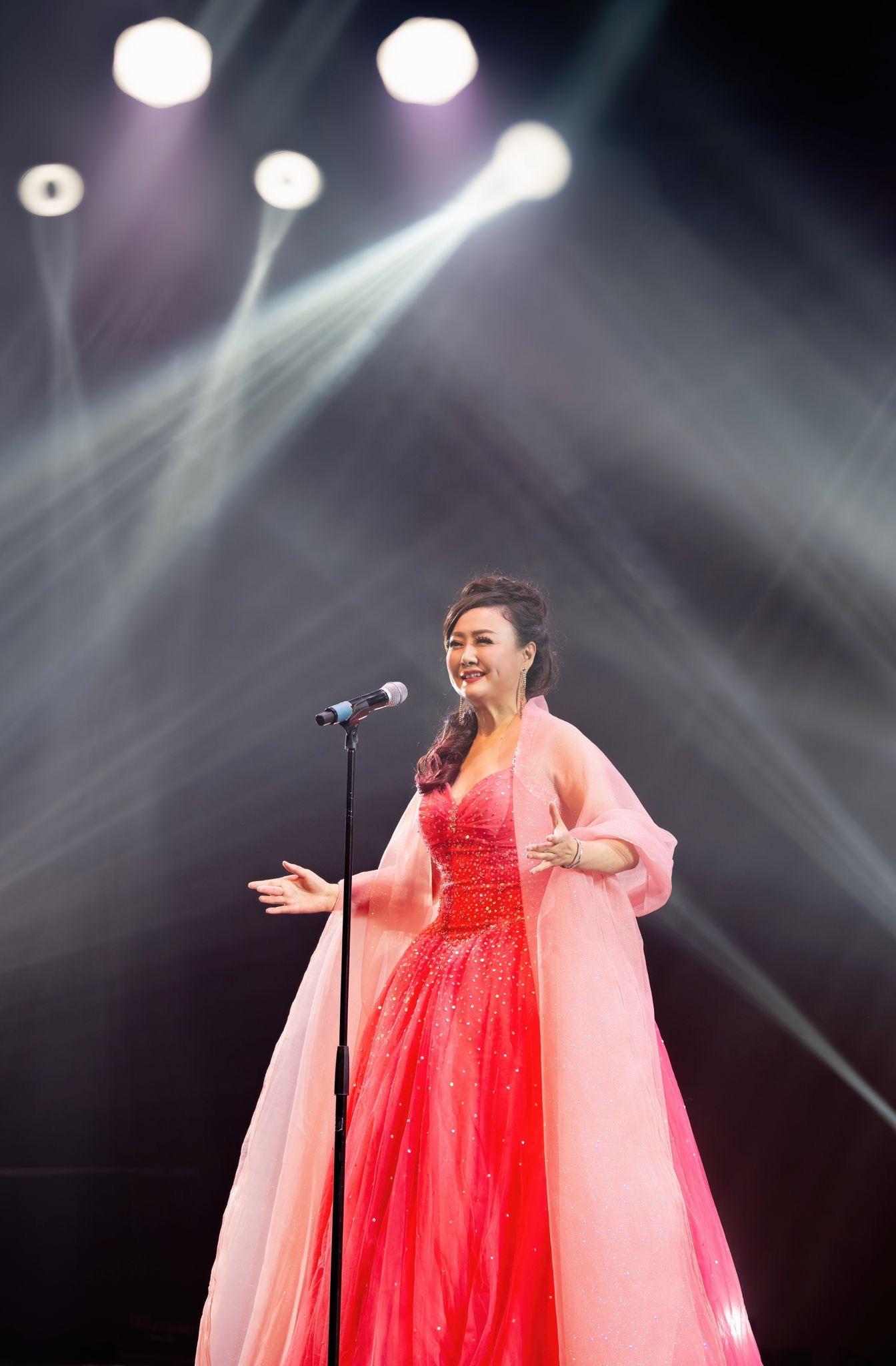 A person in a red dress with a microphone

Description automatically generated