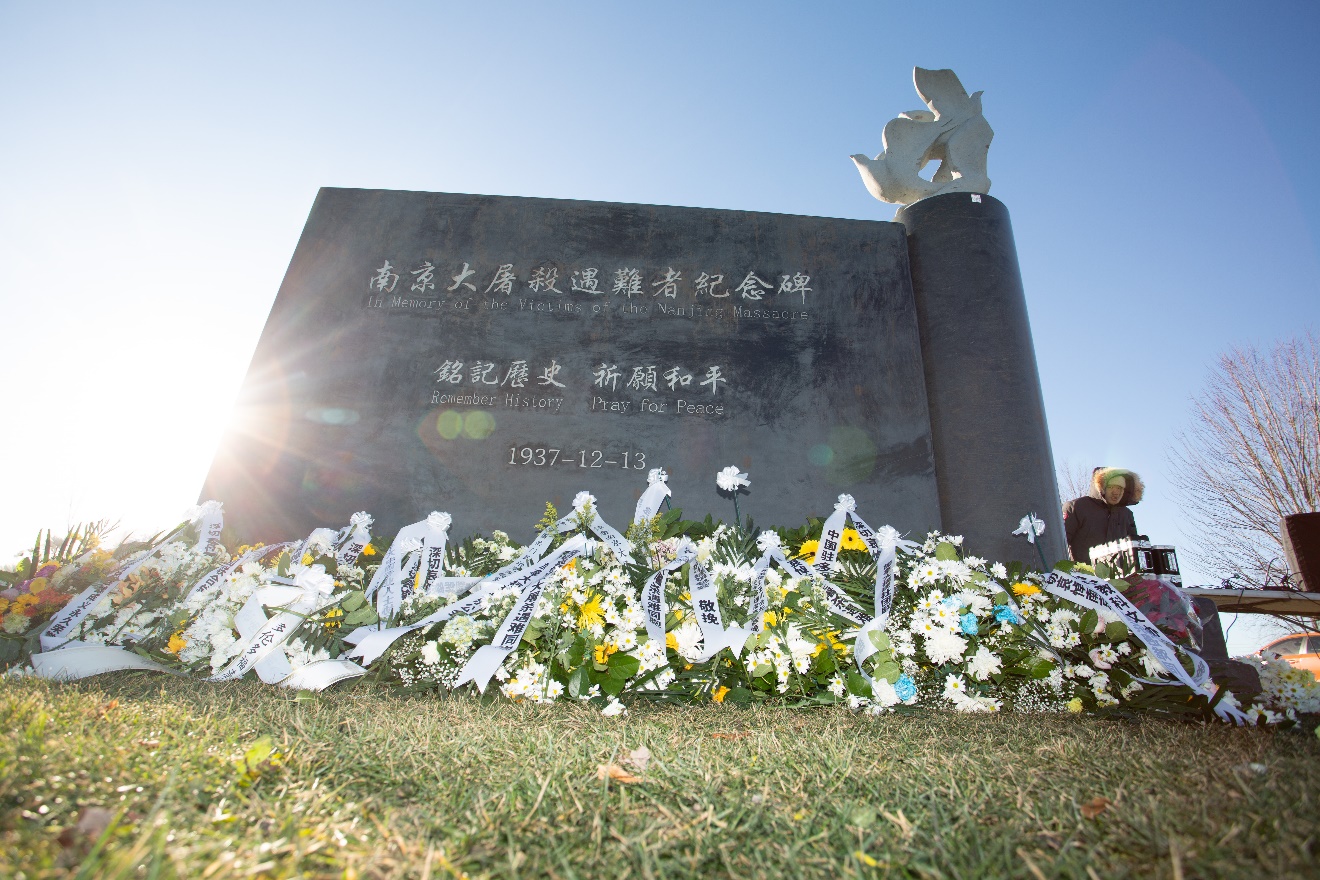 A grave stone with flowers on the ground Description automatically generated