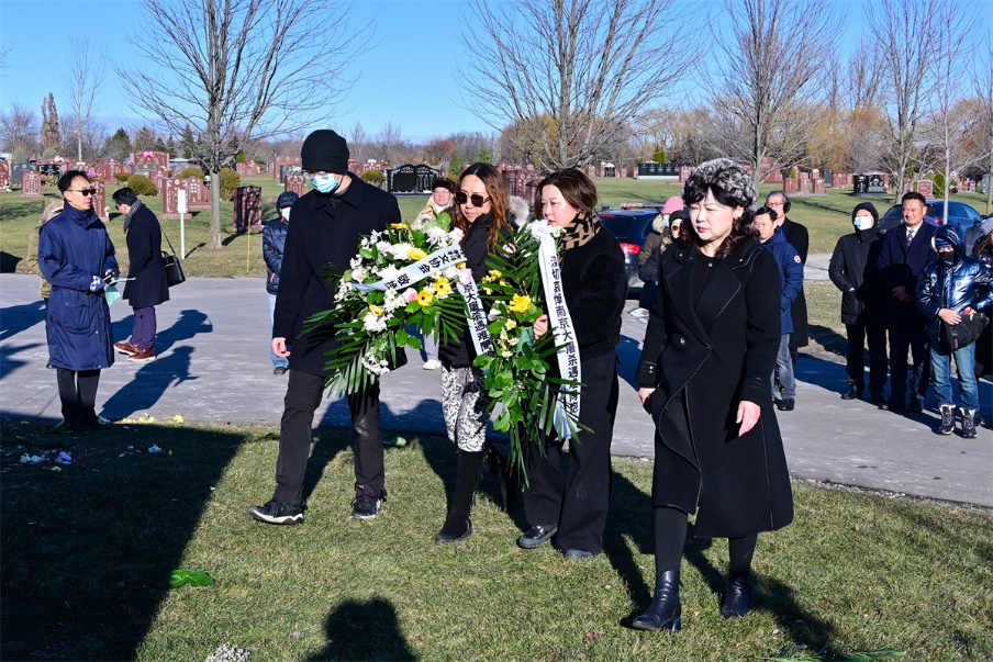 A group of people standing in a cemetery Description automatically generated