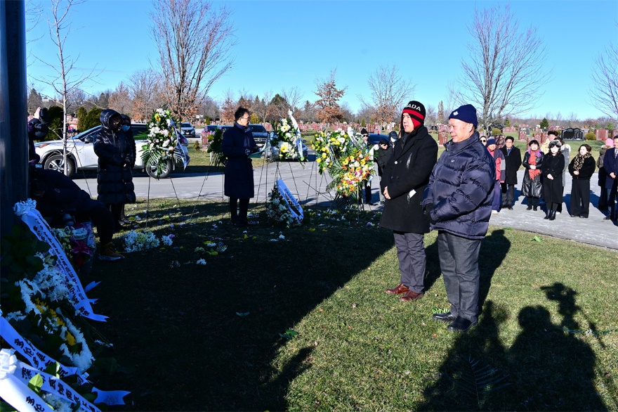 A group of people standing in a cemetery Description automatically generated