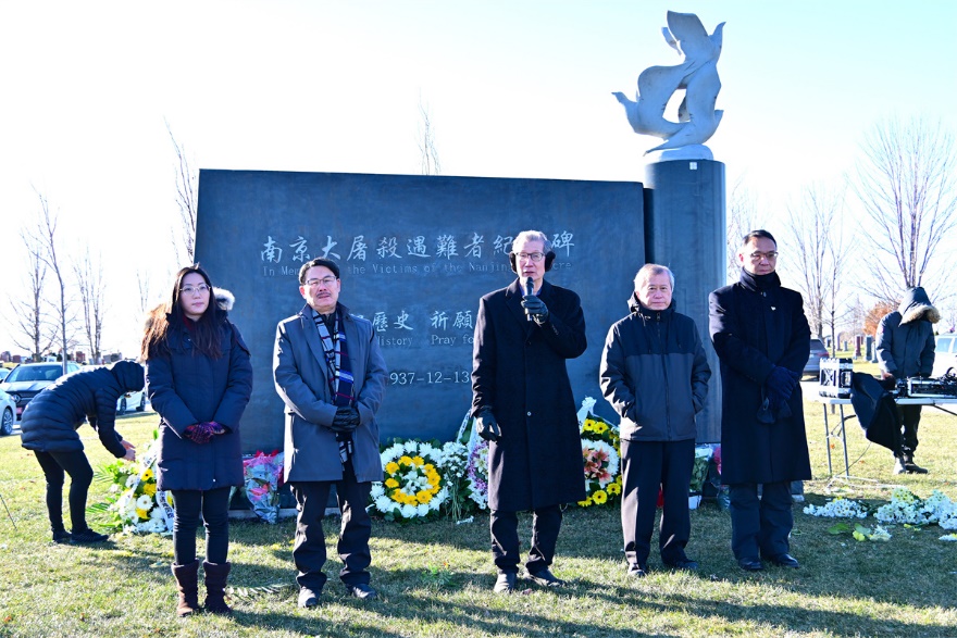 A group of people standing in front of a sign Description automatically generated