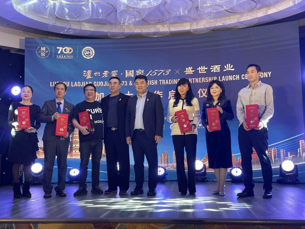 A group of people standing on a stage holding red plaques Description automatically generated