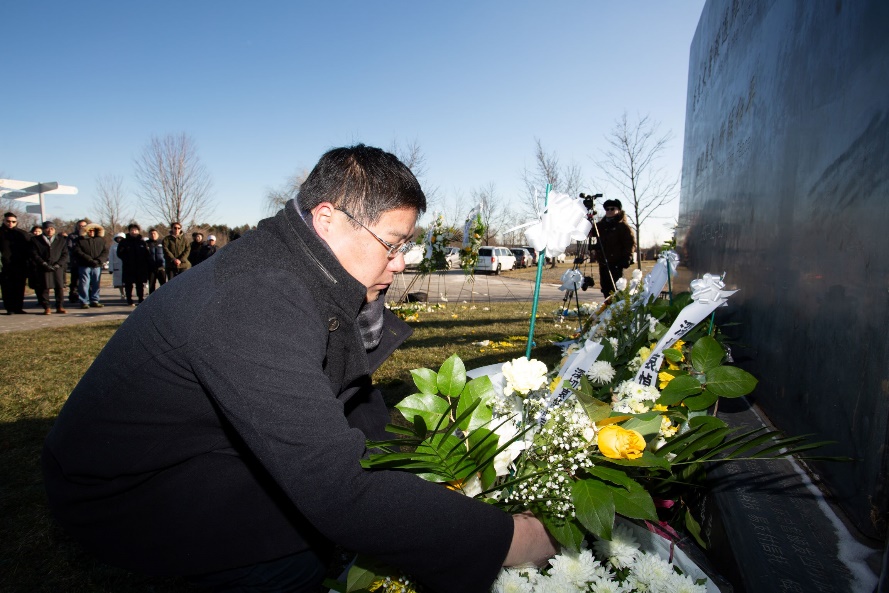 A person placing flowers on a grave Description automatically generated