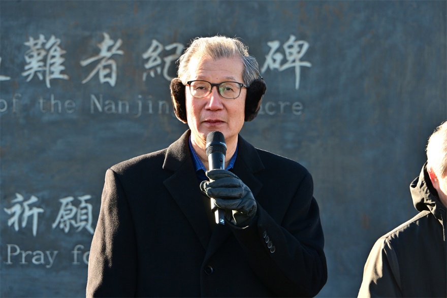 A person wearing ear muffs and a black coat holding a microphone Description automatically generated