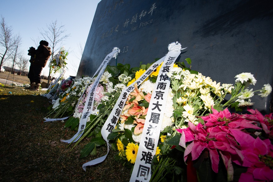 Flowers on the ground next to a grave Description automatically generated